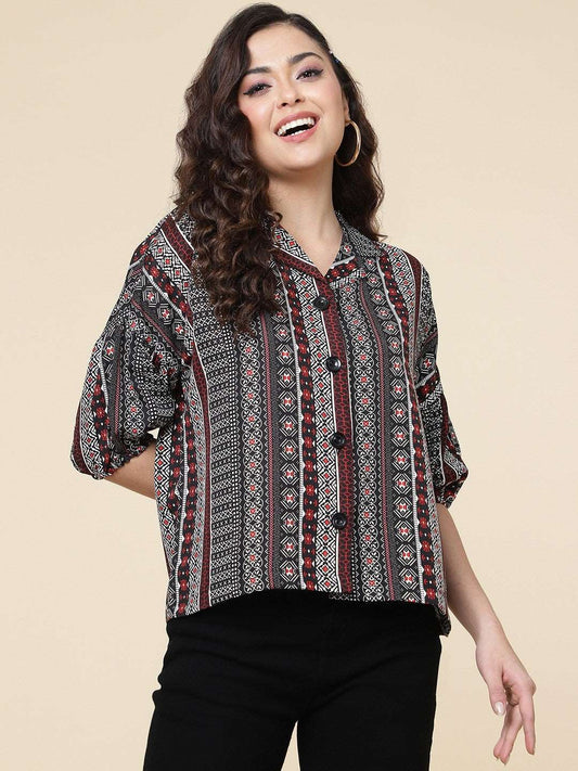The model in the image is wearing Black Colour Printed Casual Wear Rayon Shirt For Women from Alice Milan. Crafted with the finest materials and impeccable attention to detail, the Western Wear Top looks premium, trendy, luxurious and offers unparalleled comfort. It’s a perfect clothing option for loungewear, resort wear, party wear or for an airport look. The woman in the image looks happy, and confident with her style statement putting a happy smile on her face.