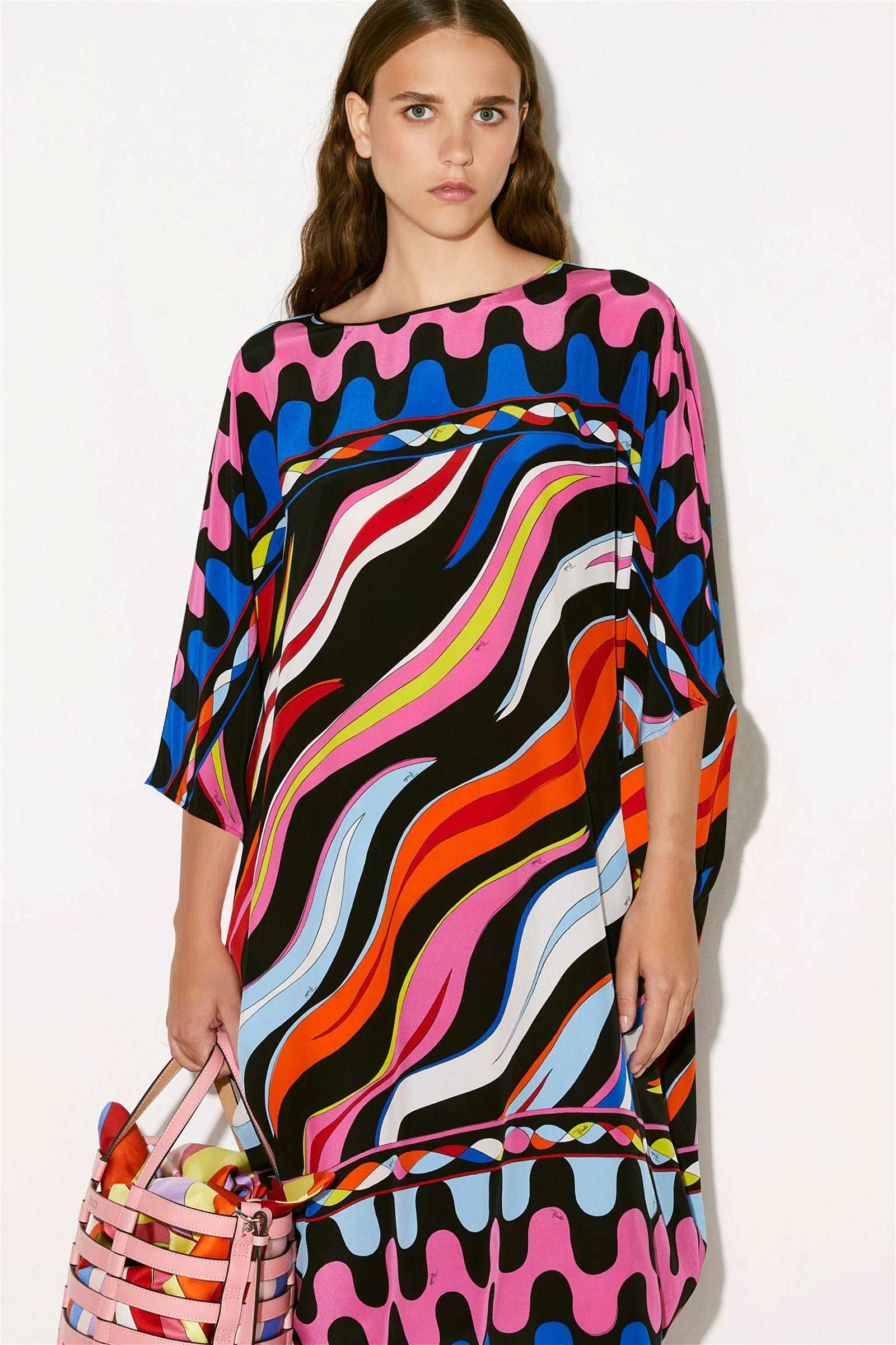 The model in the image is wearing Printed Colorful Kaftan in Silk Crepe Fabric from Alice Milan. Crafted with the finest materials and impeccable attention to detail, the Kaftan / Dress looks premium, trendy, luxurious and offers unparalleled comfort. It’s a perfect clothing option for loungewear, resort wear, party wear or for an airport look. The woman in the image looks happy, and confident with her style statement putting a happy smile on her face.
