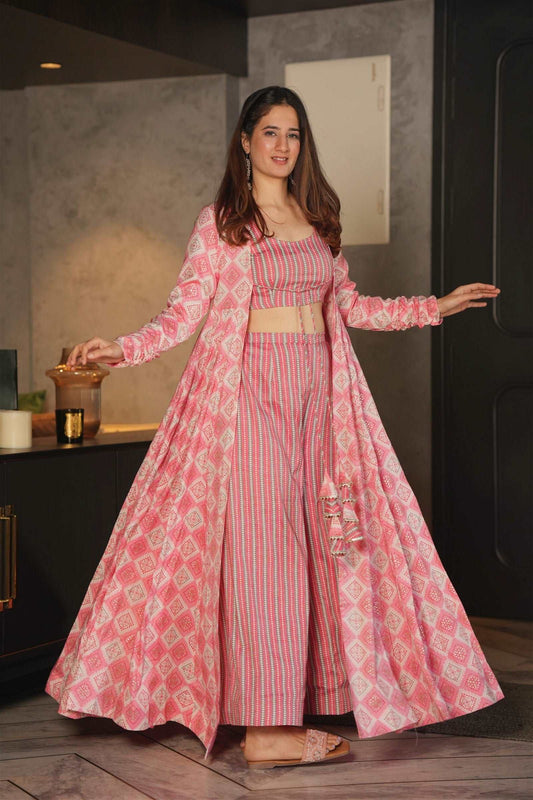 The model in the image is wearing Barbie Pink Printed Shrug Style Indo Western Gown For Women from Alice Milan. Crafted with the finest materials and impeccable attention to detail, the  looks premium, trendy, luxurious and offers unparalleled comfort. It’s a perfect clothing option for loungewear, resort wear, party wear or for an airport look. The woman in the image looks happy, and confident with her style statement putting a happy smile on her face.