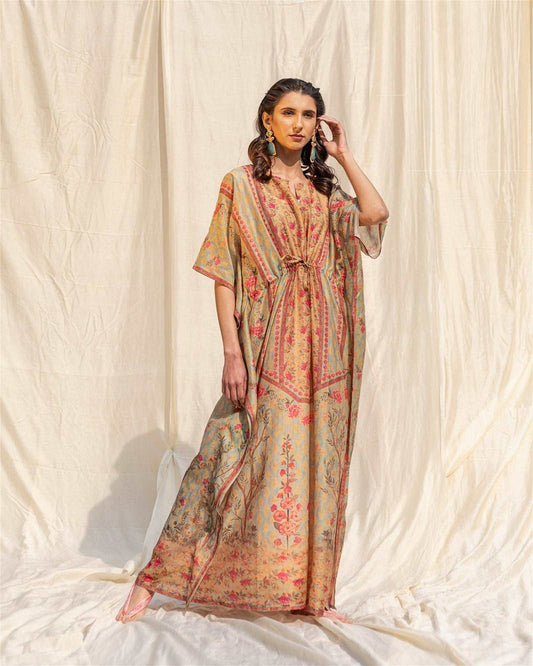 The model in the image is wearing Beige Soft Silk Premium Kaftan from Alice Milan. Crafted with the finest materials and impeccable attention to detail, the Kaftan / Dress looks premium, trendy, luxurious and offers unparalleled comfort. It’s a perfect clothing option for loungewear, resort wear, party wear or for an airport look. The woman in the image looks happy, and confident with her style statement putting a happy smile on her face.