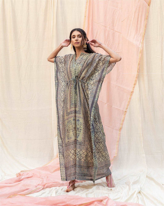 The model in the image is wearing Light Grey Silk Premium Kaftan from Alice Milan. Crafted with the finest materials and impeccable attention to detail, the Kaftan / Dress looks premium, trendy, luxurious and offers unparalleled comfort. It’s a perfect clothing option for loungewear, resort wear, party wear or for an airport look. The woman in the image looks happy, and confident with her style statement putting a happy smile on her face.
