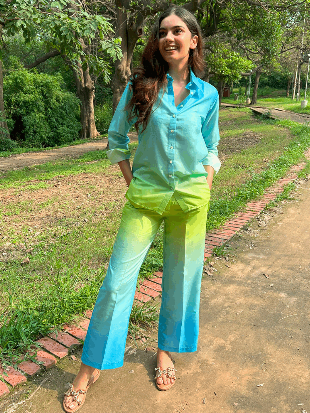 The model in the image is wearing Ombre Cotton Neon Co ord Set from Alice Milan. Crafted with the finest materials and impeccable attention to detail, the Co-ord Set looks premium, trendy, luxurious and offers unparalleled comfort. It’s a perfect clothing option for loungewear, resort wear, party wear or for an airport look. The woman in the image looks happy, and confident with her style statement putting a happy smile on her face.
