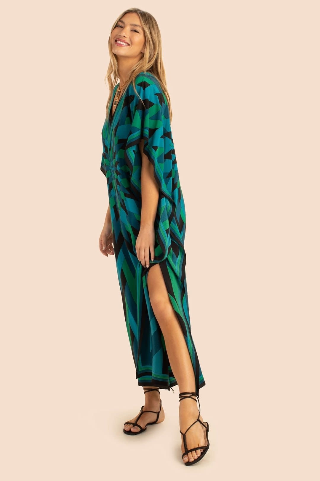 The model in the image is wearing Green Colour Soft Silk  Daily Wear Women Kaftan from Alice Milan. Crafted with the finest materials and impeccable attention to detail, the Kaftan / Dress looks premium, trendy, luxurious and offers unparalleled comfort. It’s a perfect clothing option for loungewear, resort wear, party wear or for an airport look. The woman in the image looks happy, and confident with her style statement putting a happy smile on her face.