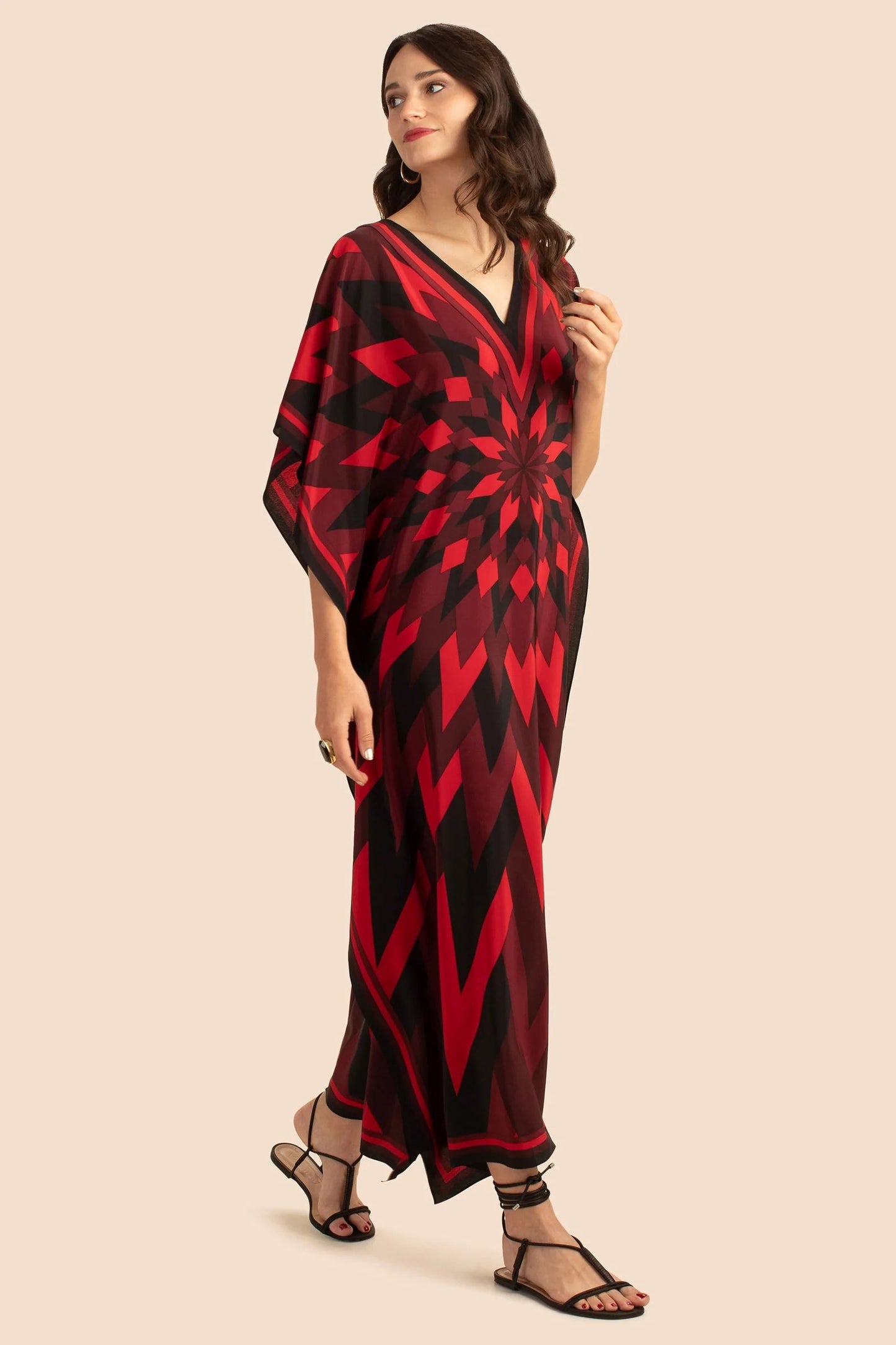 The model in the image is wearing Red Colour Soft Silk  Daily Wear Women Kaftan from Alice Milan. Crafted with the finest materials and impeccable attention to detail, the Kaftan / Dress looks premium, trendy, luxurious and offers unparalleled comfort. It’s a perfect clothing option for loungewear, resort wear, party wear or for an airport look. The woman in the image looks happy, and confident with her style statement putting a happy smile on her face.
