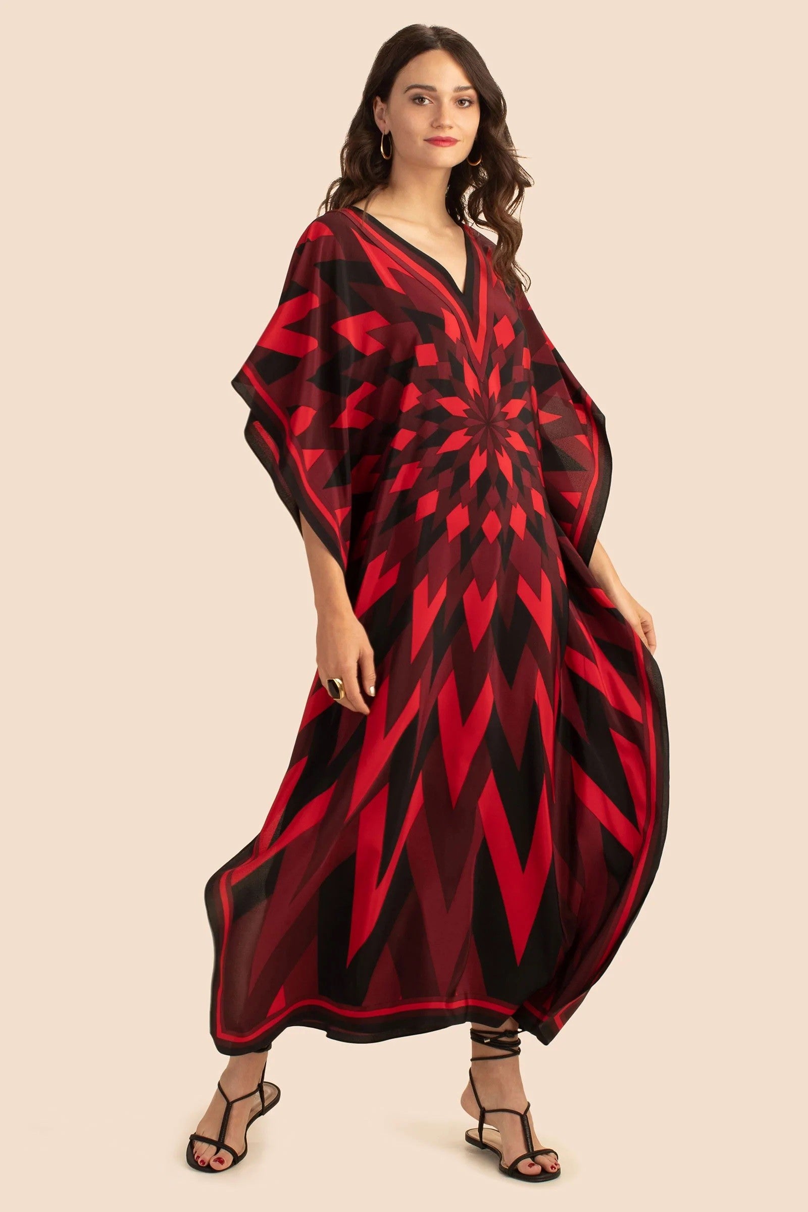 The model in the image is wearing Red Colour Soft Silk  Daily Wear Women Kaftan from Alice Milan. Crafted with the finest materials and impeccable attention to detail, the Kaftan / Dress looks premium, trendy, luxurious and offers unparalleled comfort. It’s a perfect clothing option for loungewear, resort wear, party wear or for an airport look. The woman in the image looks happy, and confident with her style statement putting a happy smile on her face.
