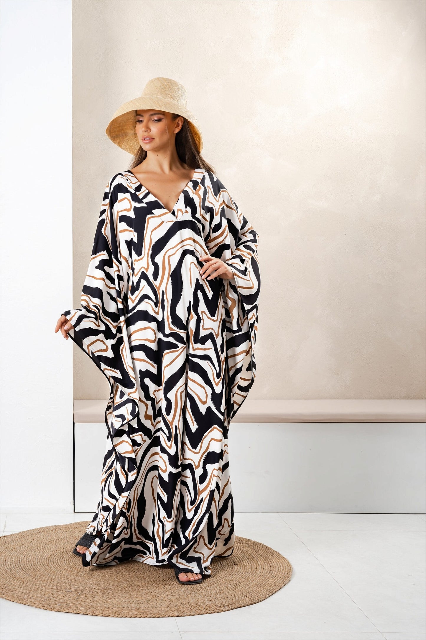 The model in the image is wearing Women Printed Long Kaftan In Silk Fabric from Alice Milan. Crafted with the finest materials and impeccable attention to detail, the Kaftan / Dress looks premium, trendy, luxurious and offers unparalleled comfort. It’s a perfect clothing option for loungewear, resort wear, party wear or for an airport look. The woman in the image looks happy, and confident with her style statement putting a happy smile on her face.