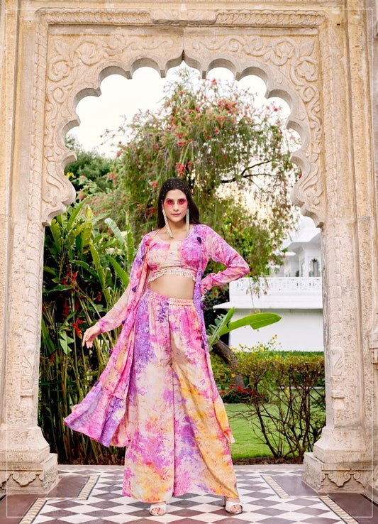 The model in the image is wearing Royal Fuchsia Tie & Dye Indo Western Suit For Women from Alice Milan. Crafted with the finest materials and impeccable attention to detail, the  looks premium, trendy, luxurious and offers unparalleled comfort. It’s a perfect clothing option for loungewear, resort wear, party wear or for an airport look. The woman in the image looks happy, and confident with her style statement putting a happy smile on her face.