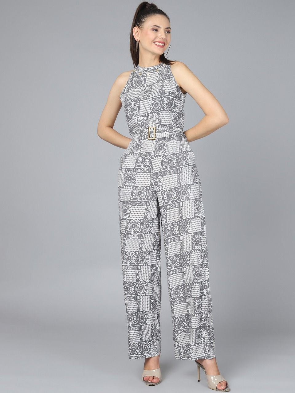 The model in the image is wearing Stylish Printed Women Jumpsuit - Grey from Alice Milan. Crafted with the finest materials and impeccable attention to detail, the Jumpsuit looks premium, trendy, luxurious and offers unparalleled comfort. It’s a perfect clothing option for loungewear, resort wear, party wear or for an airport look. The woman in the image looks happy, and confident with her style statement putting a happy smile on her face.