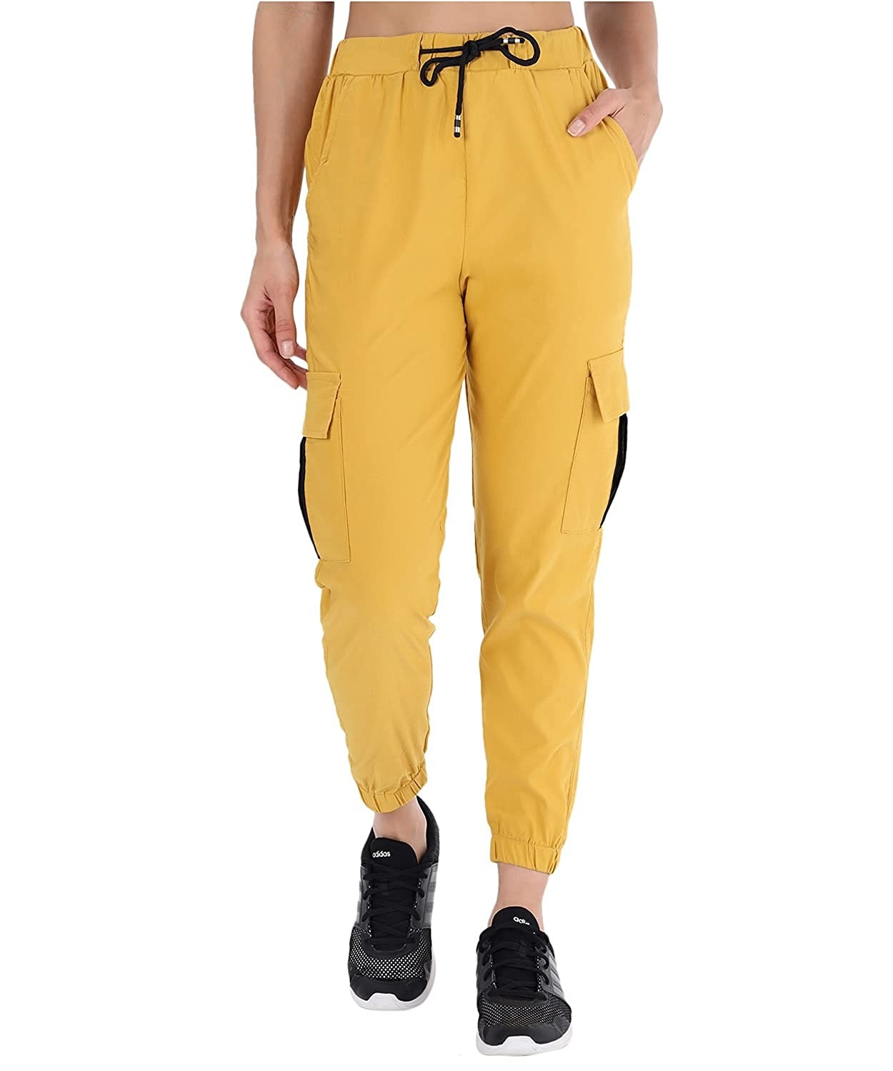 The model in the image is wearing Yellow Double Pocket Corgo Pant from Alice Milan. Crafted with the finest materials and impeccable attention to detail, the Cargo Pant looks premium, trendy, luxurious and offers unparalleled comfort. It’s a perfect clothing option for loungewear, resort wear, party wear or for an airport look. The woman in the image looks happy, and confident with her style statement putting a happy smile on her face.