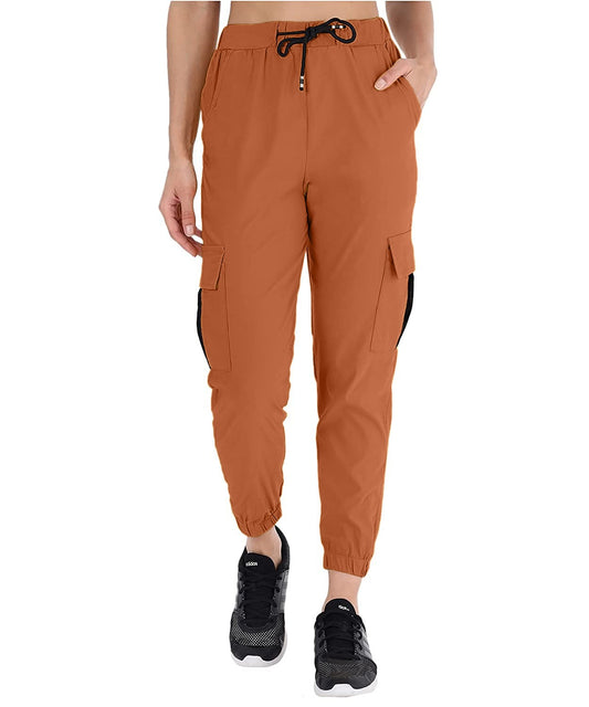 The model in the image is wearing Copper Double Pocket Corgo Pant from Alice Milan. Crafted with the finest materials and impeccable attention to detail, the Cargo Pant looks premium, trendy, luxurious and offers unparalleled comfort. It’s a perfect clothing option for loungewear, resort wear, party wear or for an airport look. The woman in the image looks happy, and confident with her style statement putting a happy smile on her face.