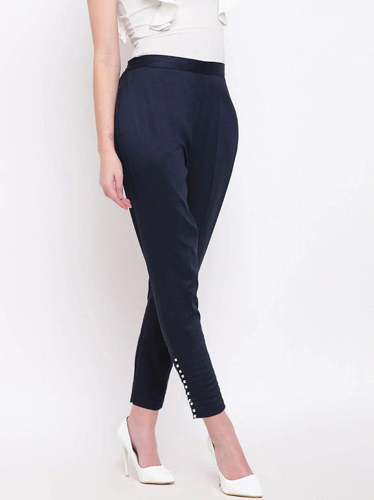 The model in the image is wearing Navy Blue Pintex Silk Women's Pant from Alice Milan. Crafted with the finest materials and impeccable attention to detail, the Women's Pant looks premium, trendy, luxurious and offers unparalleled comfort. It’s a perfect clothing option for loungewear, resort wear, party wear or for an airport look. The woman in the image looks happy, and confident with her style statement putting a happy smile on her face.