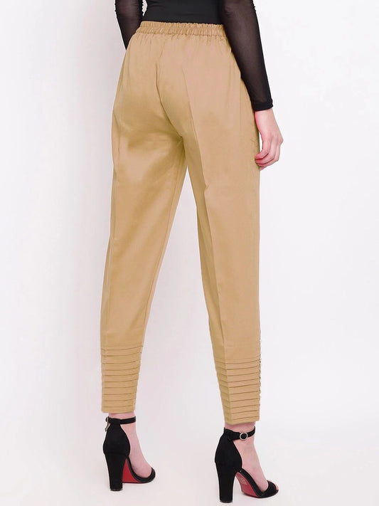 The model in the image is wearing Beige Pintex Silk Women's Pant from Alice Milan. Crafted with the finest materials and impeccable attention to detail, the Women's Pant looks premium, trendy, luxurious and offers unparalleled comfort. It’s a perfect clothing option for loungewear, resort wear, party wear or for an airport look. The woman in the image looks happy, and confident with her style statement putting a happy smile on her face.