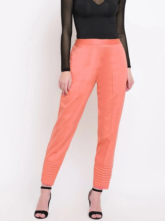 The model in the image is wearing Coral Pink Pintex Silk Women's Pant from Alice Milan. Crafted with the finest materials and impeccable attention to detail, the Women's Pant looks premium, trendy, luxurious and offers unparalleled comfort. It’s a perfect clothing option for loungewear, resort wear, party wear or for an airport look. The woman in the image looks happy, and confident with her style statement putting a happy smile on her face.