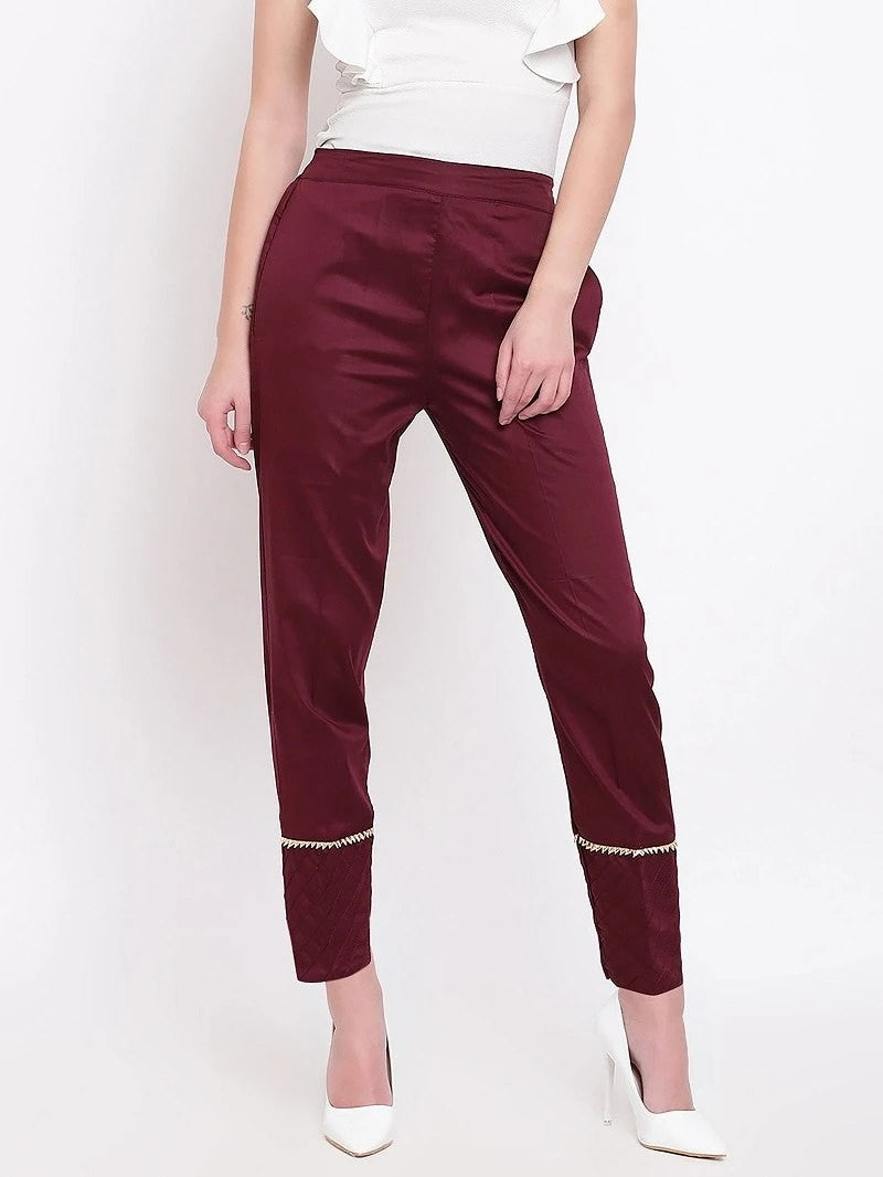 The model in the image is wearing Maroon Pant For Women from Alice Milan. Crafted with the finest materials and impeccable attention to detail, the Women's Pant looks premium, trendy, luxurious and offers unparalleled comfort. It’s a perfect clothing option for loungewear, resort wear, party wear or for an airport look. The woman in the image looks happy, and confident with her style statement putting a happy smile on her face.