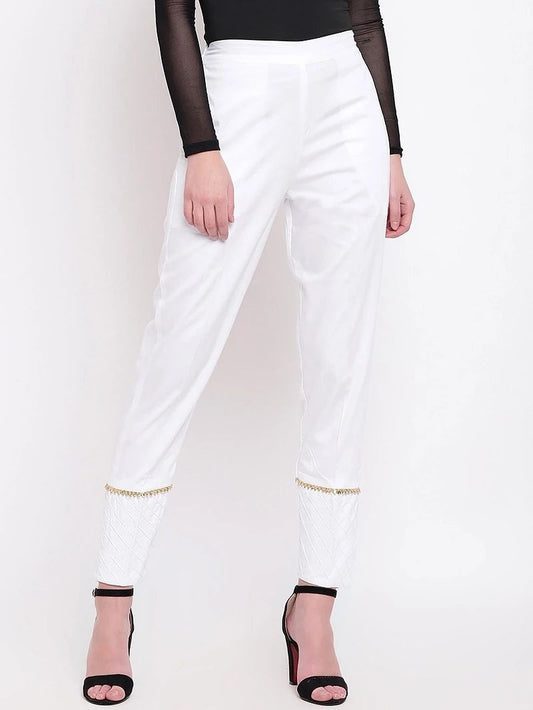 The model in the image is wearing White Pant For Women from Alice Milan. Crafted with the finest materials and impeccable attention to detail, the Women's Pant looks premium, trendy, luxurious and offers unparalleled comfort. It’s a perfect clothing option for loungewear, resort wear, party wear or for an airport look. The woman in the image looks happy, and confident with her style statement putting a happy smile on her face.
