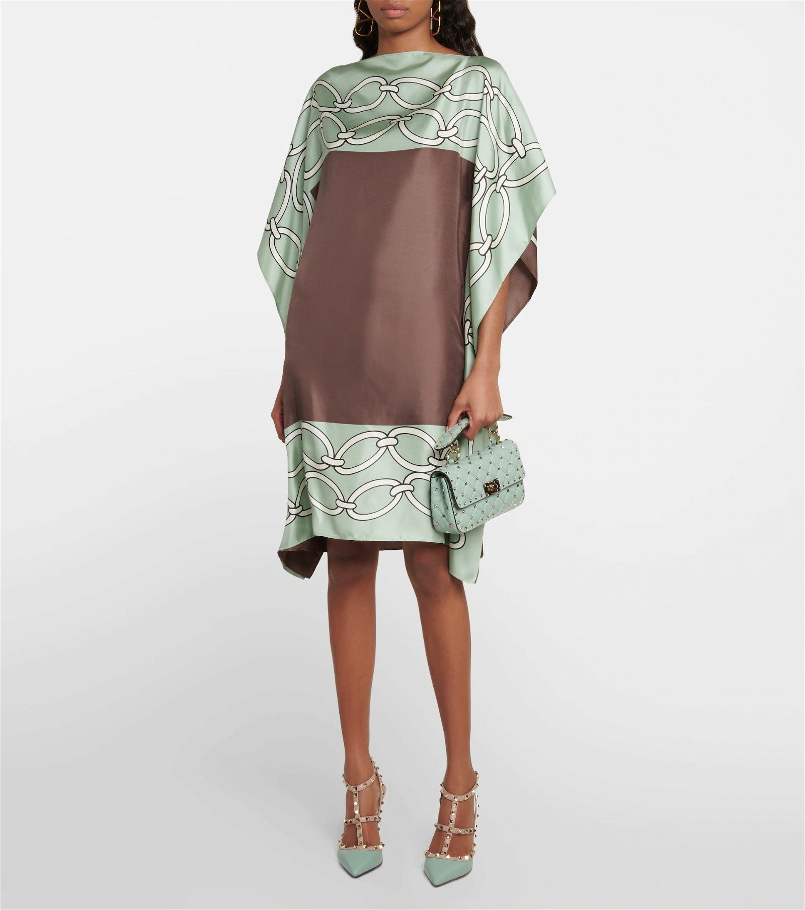 The model in the image is wearing Green Colour Printed Satin Silk Casual Wear Kaftan from Alice Milan. Crafted with the finest materials and impeccable attention to detail, the Kaftan / Dress looks premium, trendy, luxurious and offers unparalleled comfort. It’s a perfect clothing option for loungewear, resort wear, party wear or for an airport look. The woman in the image looks happy, and confident with her style statement putting a happy smile on her face.
