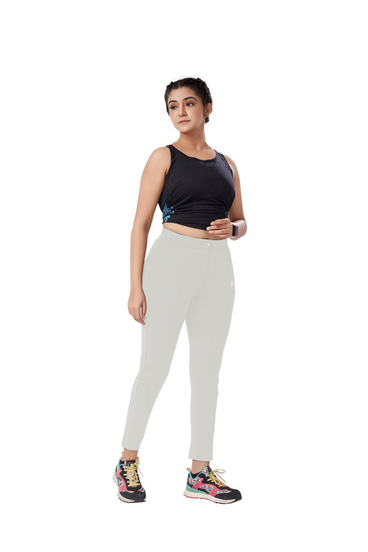 The model in the image is wearing White Colour Polyester Solid Pattern Track Pant For Women's from Alice Milan. Crafted with the finest materials and impeccable attention to detail, the Track Pant looks premium, trendy, luxurious and offers unparalleled comfort. It’s a perfect clothing option for loungewear, resort wear, party wear or for an airport look. The woman in the image looks happy, and confident with her style statement putting a happy smile on her face.