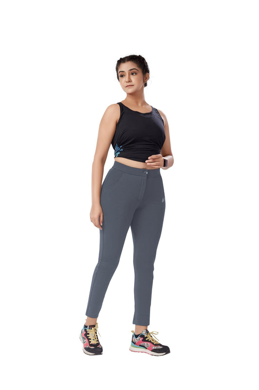 The model in the image is wearing Grey Colour Polyester Solid Pattern Track Pant For Women's from Alice Milan. Crafted with the finest materials and impeccable attention to detail, the Track Pant looks premium, trendy, luxurious and offers unparalleled comfort. It’s a perfect clothing option for loungewear, resort wear, party wear or for an airport look. The woman in the image looks happy, and confident with her style statement putting a happy smile on her face.