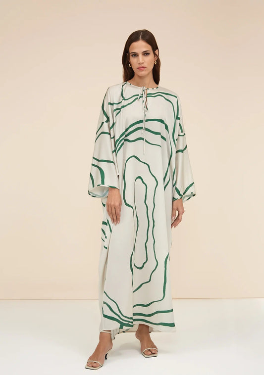 The model in the image is wearing Green Colour Printed Organza Silk Party Wear Kaftan from Alice Milan. Crafted with the finest materials and impeccable attention to detail, the Kaftan / Dress looks premium, trendy, luxurious and offers unparalleled comfort. It’s a perfect clothing option for loungewear, resort wear, party wear or for an airport look. The woman in the image looks happy, and confident with her style statement putting a happy smile on her face.