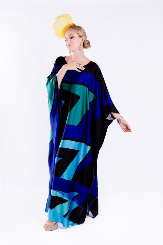 The model in the image is wearing Blue Colour Printed Satin Silk Party Wear Kaftan from Alice Milan. Crafted with the finest materials and impeccable attention to detail, the Partywear Dress looks premium, trendy, luxurious and offers unparalleled comfort. It’s a perfect clothing option for loungewear, resort wear, party wear or for an airport look. The woman in the image looks happy, and confident with her style statement putting a happy smile on her face.