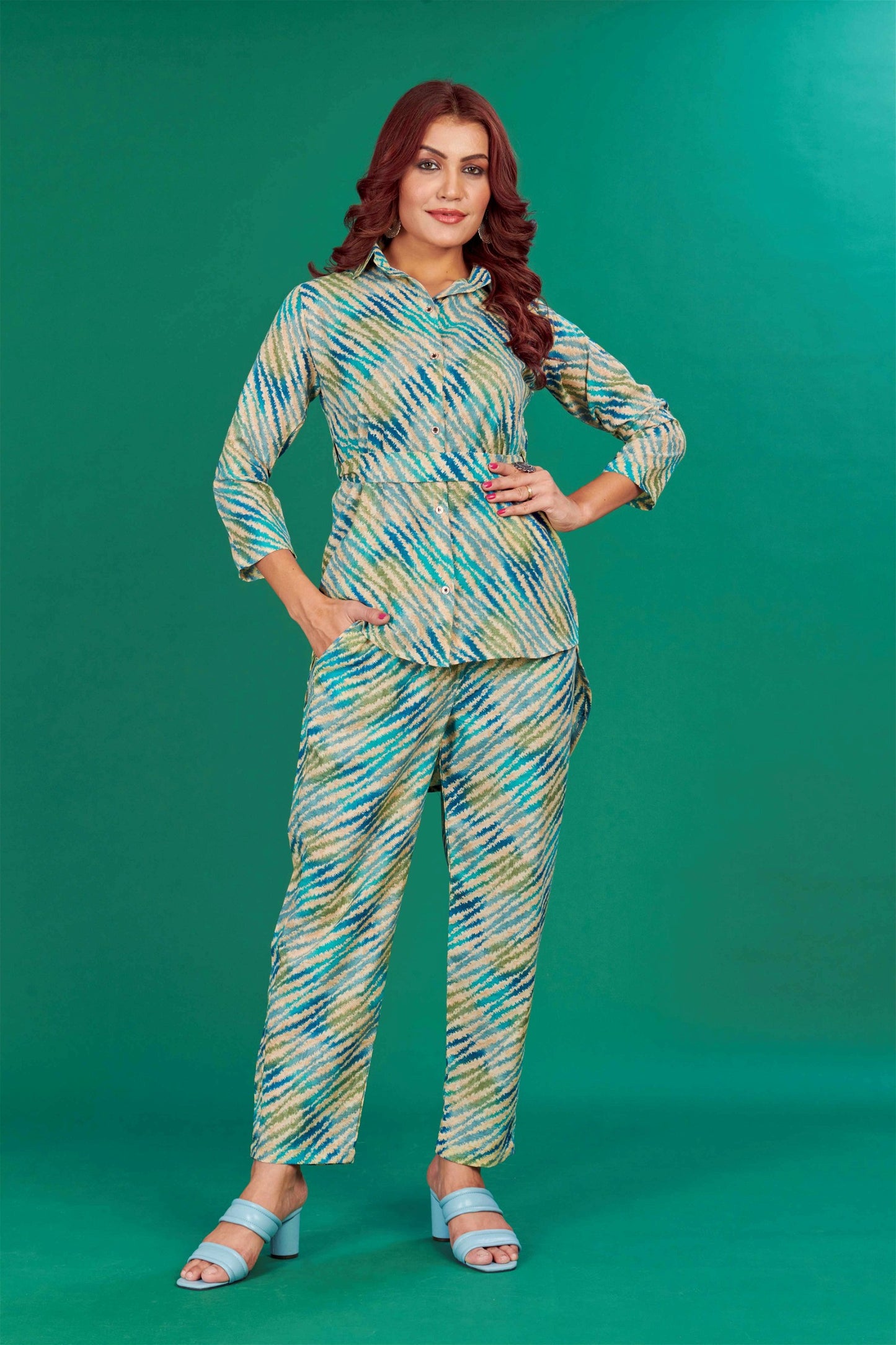 The model in the image is wearing Teal Cotton Party Wear Co-ords Set from Alice Milan. Crafted with the finest materials and impeccable attention to detail, the  looks premium, trendy, luxurious and offers unparalleled comfort. It’s a perfect clothing option for loungewear, resort wear, party wear or for an airport look. The woman in the image looks happy, and confident with her style statement putting a happy smile on her face.