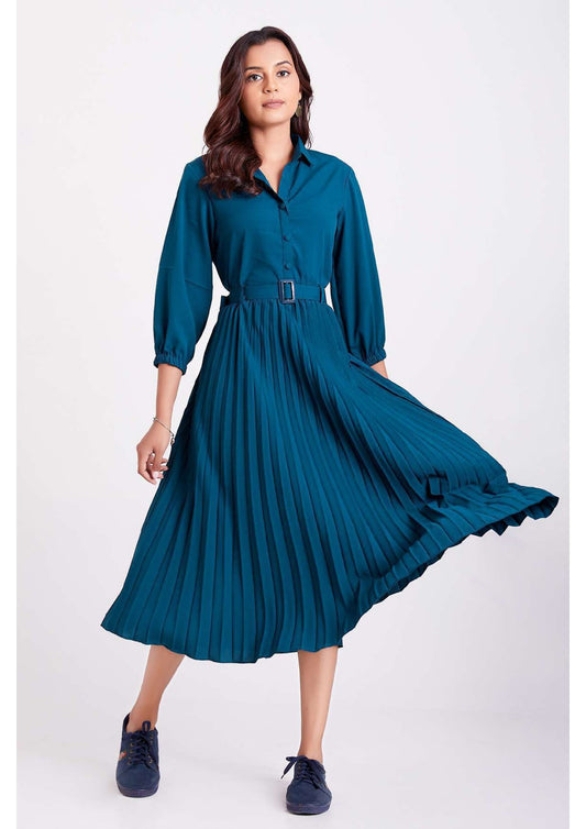 The model in the image is wearing Teal Blue Colour Pleated Western Wear Drees For Women from Alice Milan. Crafted with the finest materials and impeccable attention to detail, the Dress looks premium, trendy, luxurious and offers unparalleled comfort. It’s a perfect clothing option for loungewear, resort wear, party wear or for an airport look. The woman in the image looks happy, and confident with her style statement putting a happy smile on her face.