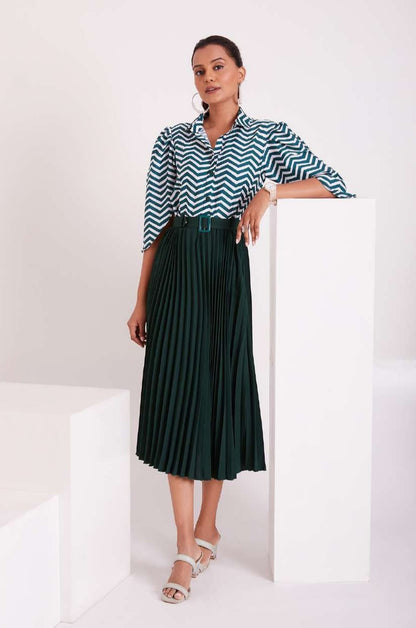 The model in the image is wearing Green and White Pleated Western Wear Stylish Dress For Women from Alice Milan. Crafted with the finest materials and impeccable attention to detail, the Dress looks premium, trendy, luxurious and offers unparalleled comfort. It’s a perfect clothing option for loungewear, resort wear, party wear or for an airport look. The woman in the image looks happy, and confident with her style statement putting a happy smile on her face.