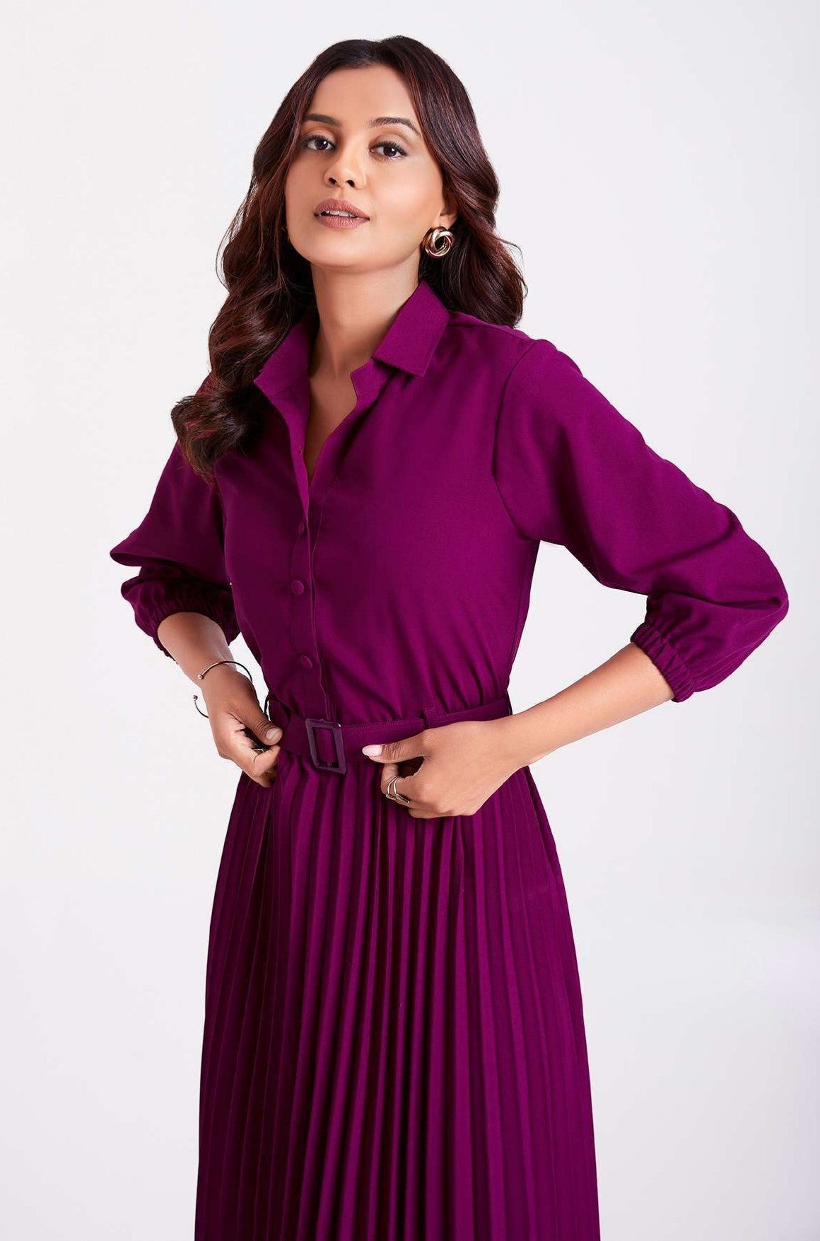 The model in the image is wearing Purple Pan Collar Pleated Western Wear dress for women from Alice Milan. Crafted with the finest materials and impeccable attention to detail, the Dress looks premium, trendy, luxurious and offers unparalleled comfort. It’s a perfect clothing option for loungewear, resort wear, party wear or for an airport look. The woman in the image looks happy, and confident with her style statement putting a happy smile on her face.