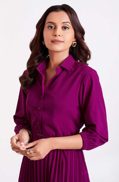 The model in the image is wearing Purple Pan Collar Pleated Western Wear dress for women from Alice Milan. Crafted with the finest materials and impeccable attention to detail, the Dress looks premium, trendy, luxurious and offers unparalleled comfort. It’s a perfect clothing option for loungewear, resort wear, party wear or for an airport look. The woman in the image looks happy, and confident with her style statement putting a happy smile on her face.