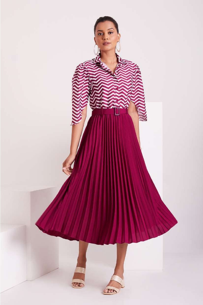 The model in the image is wearing Purple and White Pleated Western Wear Stylish Dress For Women from Alice Milan. Crafted with the finest materials and impeccable attention to detail, the Dress looks premium, trendy, luxurious and offers unparalleled comfort. It’s a perfect clothing option for loungewear, resort wear, party wear or for an airport look. The woman in the image looks happy, and confident with her style statement putting a happy smile on her face.